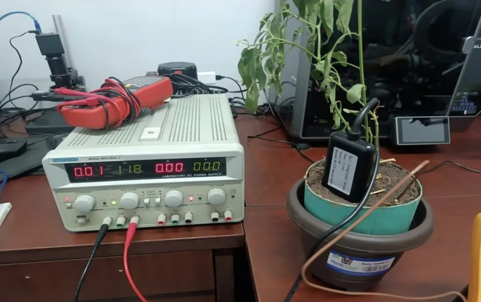 Prototipo físico de PICS: sensor de humedad en una maceta con planta conectado a una fuente de alimentación de laboratorio